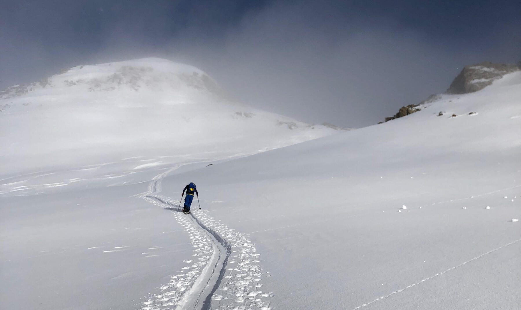 A ski tourer climbing a snowy slope toward a misty summit